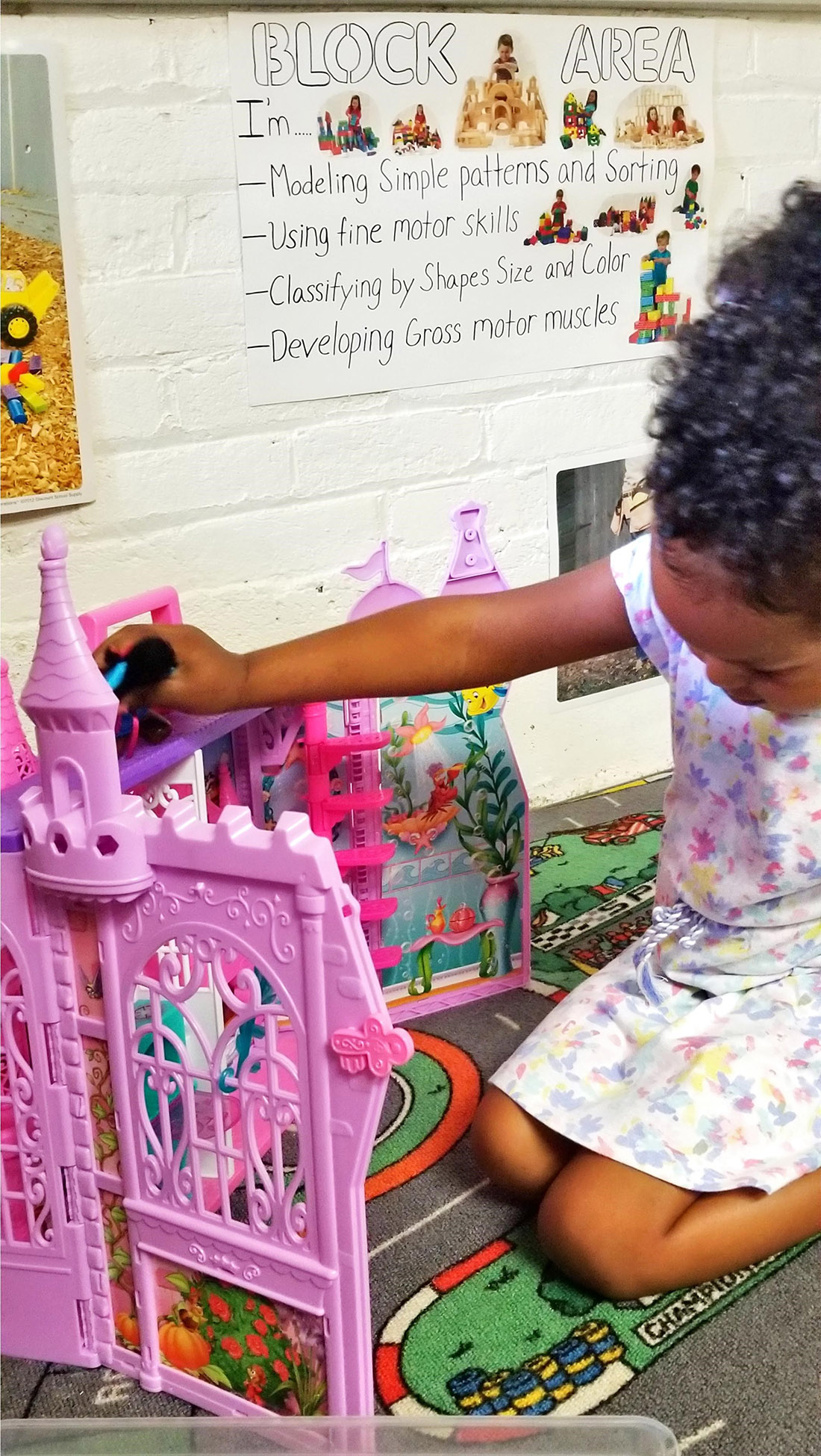 Girl plays with pink dollhouse at Childcare Center and daycare at New Beginnings